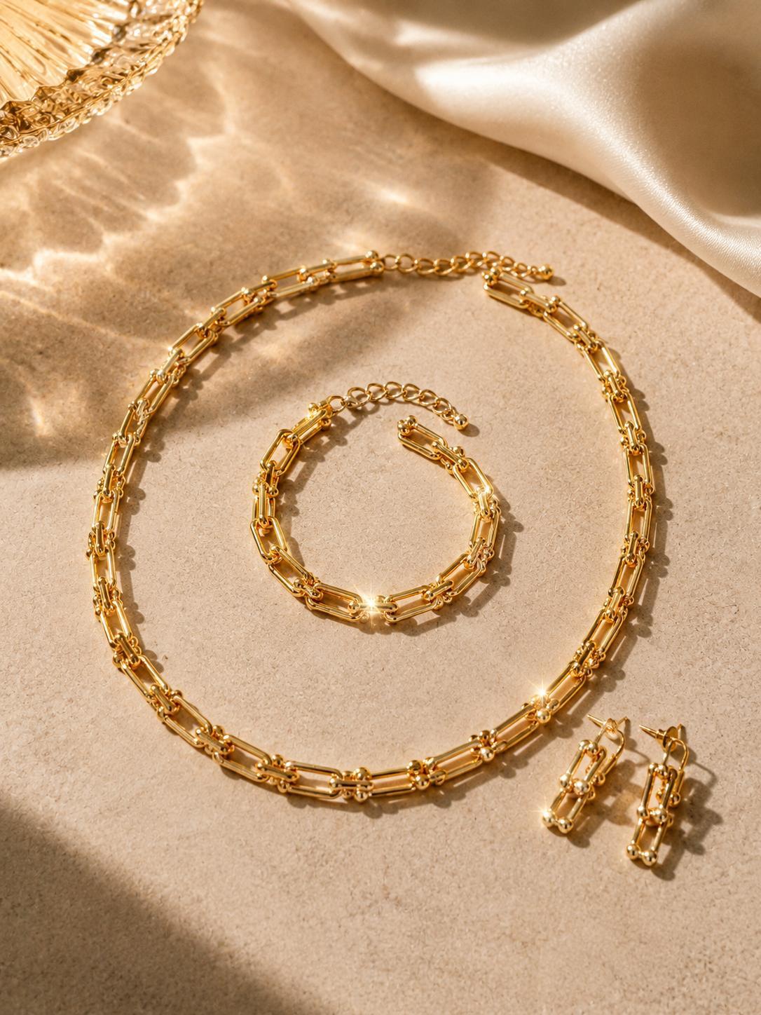 Parure MATHYLDIS completa: collana, bracciale e orecchini oro su fondo chiaro